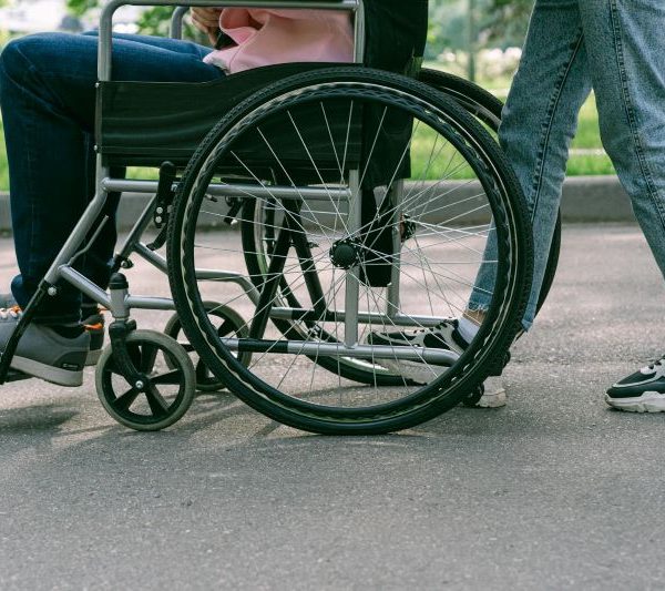 A caregiver pushes a person in a wheelchair.