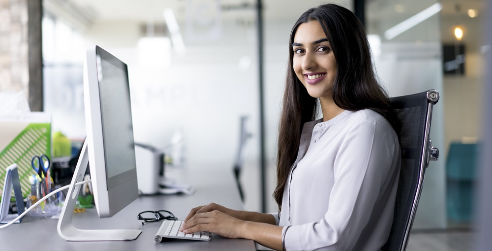 a woman smiling while working on a computer